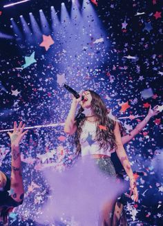 a woman standing on top of a stage with confetti in the air behind her