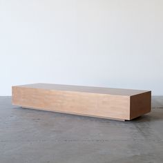 a large wooden box sitting on top of a cement floor next to a white wall