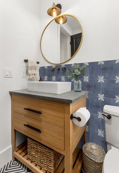 a white toilet sitting next to a bathroom sink under a mirror above a wooden vanity