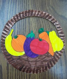 a paper plate with fruit and vegetables on it in the shape of a circle, sitting on a wooden surface