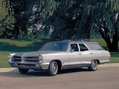 an old station wagon is parked on the side of the road in front of some trees