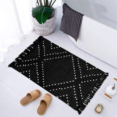 a black and white rug on the floor next to slippers, plant and other items