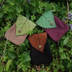 four leaf shaped purses sitting on top of green grass next to leaves and plants