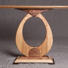 a wooden table with an oval design on the top and two circular sections at the base