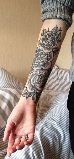 a woman's arm with a rose tattoo on her left hand and a ring in the middle