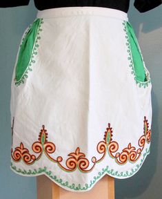 a woman's apron with green and orange trimmings on a mannequin