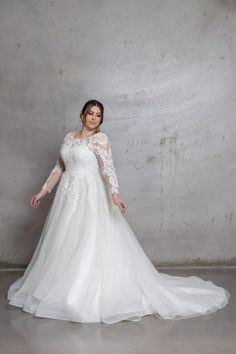 a woman in a white wedding dress posing for the camera with her hands on her hips