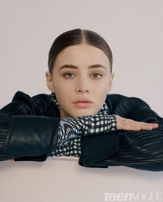 a woman wearing a black and white checkered shirt with her hands on her chest