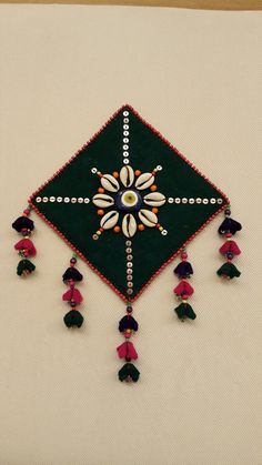 an embroidered wall hanging with tassels and beads on the bottom half of it