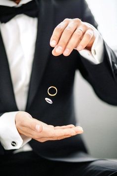 a man in a tuxedo is holding out his hand with a ring on it