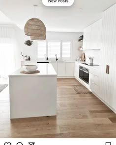 a large white kitchen with wooden floors and an island in the middle, along with wicker baskets hanging from the ceiling