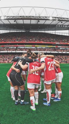 a group of women standing on top of a field in front of a soccer stadium