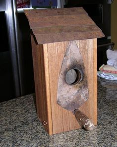 an old wooden birdhouse with a hammer sticking out of it's center hole