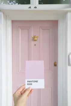 a person holding up a pink door with the name pantone on it