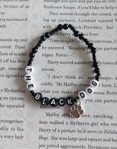 a black beaded bracelet with a dog's paw and name charm on it