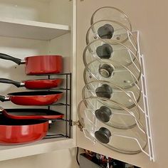 pots and pans are hanging on the wall in a kitchen cabinet with shelves holding utensils