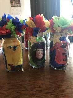 three glass jars filled with different colored paper flowers