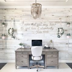 a desk with a computer on it in front of a wall that has words written on it