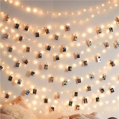 there are pictures hanging on the wall with lights strung from it and photos hung above them