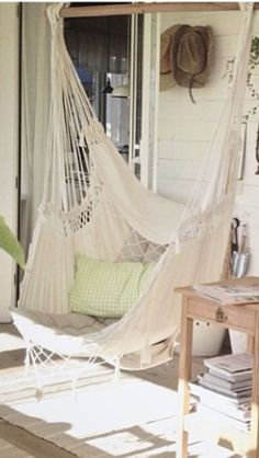 a white hammock sitting on top of a wooden floor next to a table