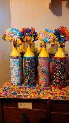 four colorful vases with flowers in them on a table