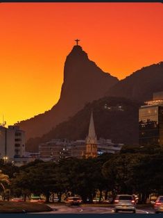 the sun is setting over a city with mountains in the background and cars driving on the road