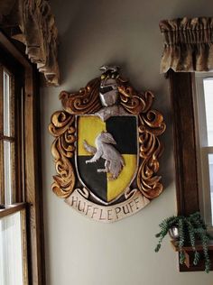 there is a coat of arms on the wall above the window and below it is a potted plant