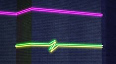 a neon sign on the side of a brick wall that is lit up in different colors