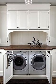 a washer and dryer in a room with white cupboards on the wall