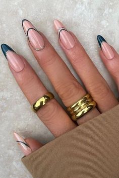 a woman's hand with two gold rings on it and some pink nail polish