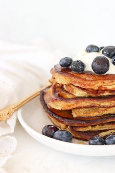 a stack of pancakes topped with blueberries and whipped cream