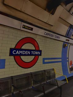 a train station with benches and a sign on the wall that says camden town in english