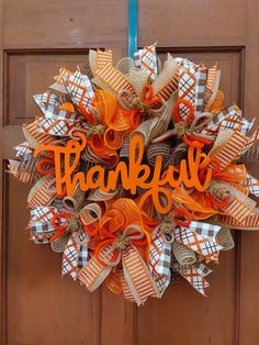 an orange and white wreath with the word happy on it hanging from a wooden door