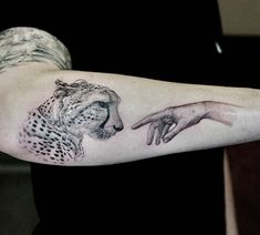 a tattoo on the arm of a man with a cheetah and hand pointing at it