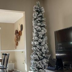 a living room with a christmas tree next to a flat screen tv on a stand