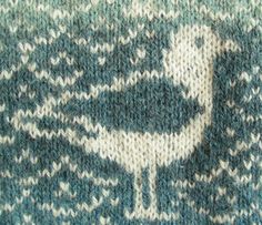 a blue and white knitted sweater with a bird design on the front, side