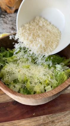 a wooden bowl filled with lettuce and grated cheese