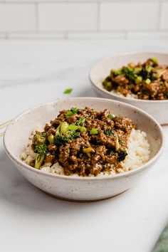 two bowls filled with meat and vegetables on top of rice