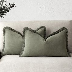 two green pillows sitting on top of a white couch