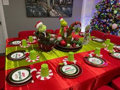 the table is set for christmas dinner with green and red plates, silverware, and candy canes