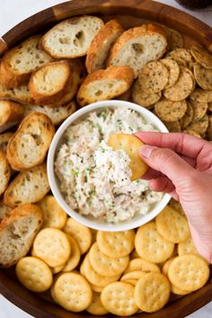 a person dipping crackers into a bowl of dip