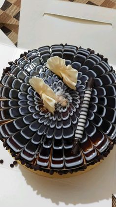 a chocolate cake with white and black decorations on it's top, sitting in a box