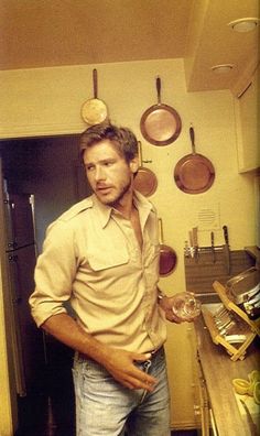 a man standing in a kitchen with pots and pans on the wall