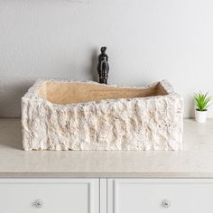 a white sink sitting on top of a counter next to a potted green plant