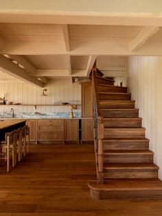 a kitchen with wooden floors and stairs leading up to the upper floor, next to an island