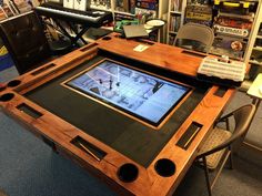 a wooden table with an electronic device on it in a room full of books and video games