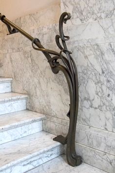 an iron handrail on the side of a marble staircase