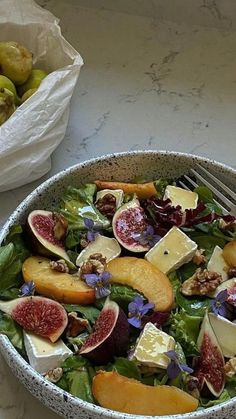 a bowl filled with salad next to a bag of fruit