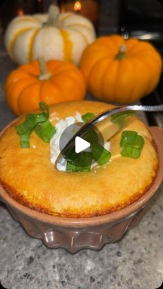 a bowl filled with food next to pumpkins