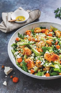 a salad with cauliflower, lettuce and carrots in a bowl